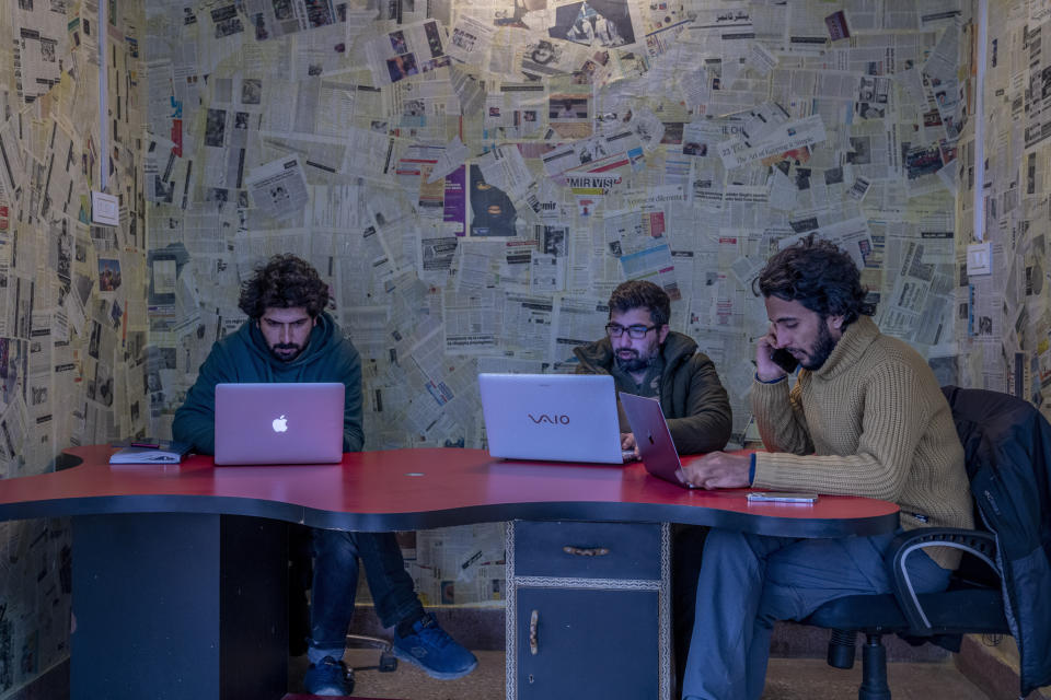 Fahad Shah, right, editor-in-chief of Kashmir Walla, works on his computer inside the newsroom at his office in Srinagar, Indian controlled Kashmir, Friday, Jan. 21, 2022. Shah said he has been summoned by police several times and also detained once regarding his stories on Kashmir after the abrogation of article 370. Media has always been tightly controlled in India’s part of Muslim-majority Kashmir. But their situation has gotten dramatically worse since India revoked the region’s semi-autonomy in 2019, throwing Kashmir under a security and communication lockdown. Journalists have been arrested, interrogated and investigated under harsh anti-terror laws. (AP Photo/Dar Yasin)