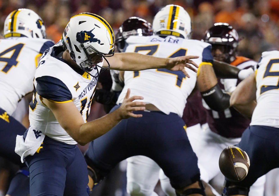 West Virginia quarterback JT Daniels (18) loses control of the ball during the first half of the team's NCAA college football game against Virginia Tech on hursday, Sept. 22, 2022, in Blacksburg, Va. (AP Photo/Steve Helber)