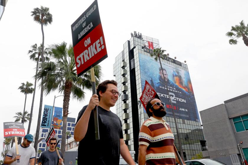 LOS ANGELES, CA - JUNE 05: Picketers with the Writers Guild of America (WGA) strike outside the Sunset Bronson Studios along Sunset Blvd. on Monday, June 5, 2023 in Los Angeles, CA. The WGA is entering its' sixth week of the walkout. The Directors Guild of America said it has reached a "historic deal" with the major studios on a new three-year film and TV contract. A Netflix building is seen in the background. (Gary Coronado / Los Angeles Times)