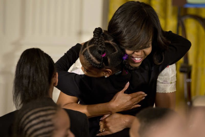 白宮「親子上班日」，讓員工可以帶小孩上班，蜜雪兒一一擁抱白宮工作人員的孩子。（美聯社）