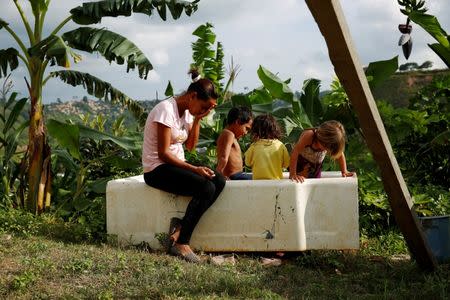 Lisibeht Martinez (L), 30, who was sterilized one year ago, sits next to her children while they play in a bathtub in the backyard of their house in Los Teques, Venezuela July 19, 2016. REUTERS/Carlos Garcia Rawlins