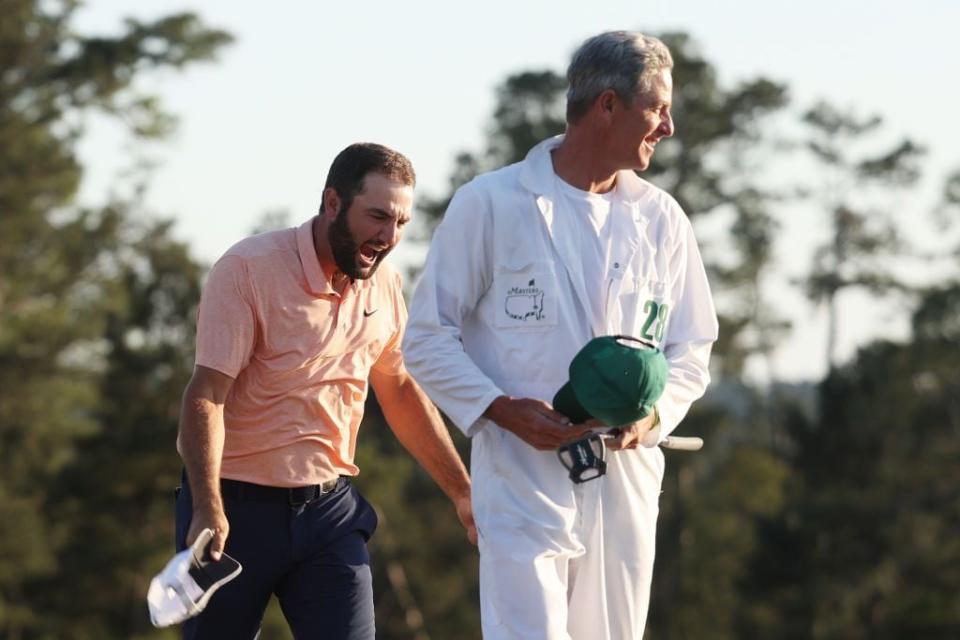 Scottie Scheffler and caddie Ted Scott celebrate on the 18th green after winning the 2024 Masters.