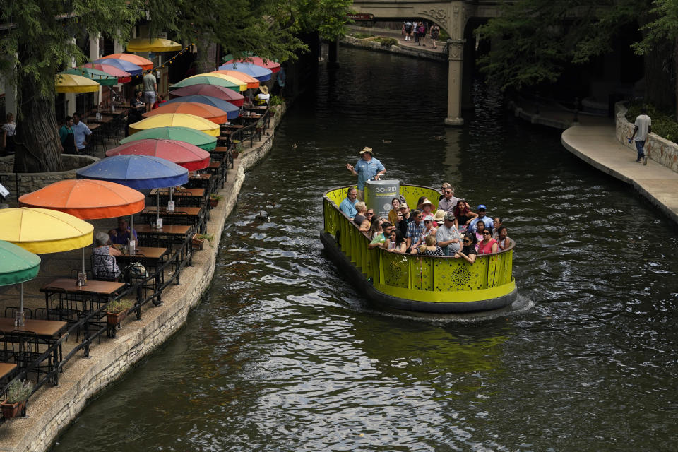 A barge tours along the Riverwalk, Friday, June 17, 2022, in San Antonio. The summer of 2022 can feel as if the coronavirus pandemic is really over. Mask rules and testing requirements are lifting in many countries, including the United States. (AP Photo/Eric Gay)