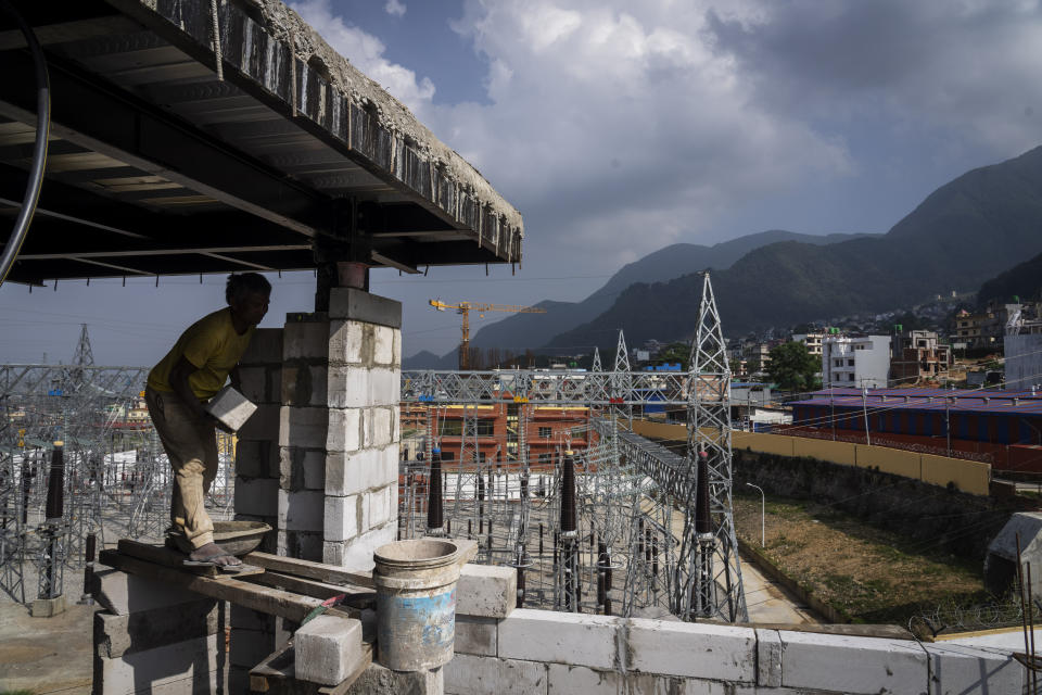 A laborer works at a construction site next to a power station at Matatirtha on the outskirts of Kathmandu, Nepal, Friday, May 31, 2024. Nepal’s abundant hydroelectric power is helping the Himalayan nation cut its oil imports and clean up its air, thanks to a boom in sales of electric vehicles. (AP Photo/Niranjan Shrestha)