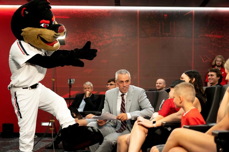 Cincinnati Bearcats head baseball coach Jordan Bischel sits with his family as the Bearcat mascot greets them before a press conference at the Lindner Center in Cincinnati on Wednesday, June 21, 2023. 