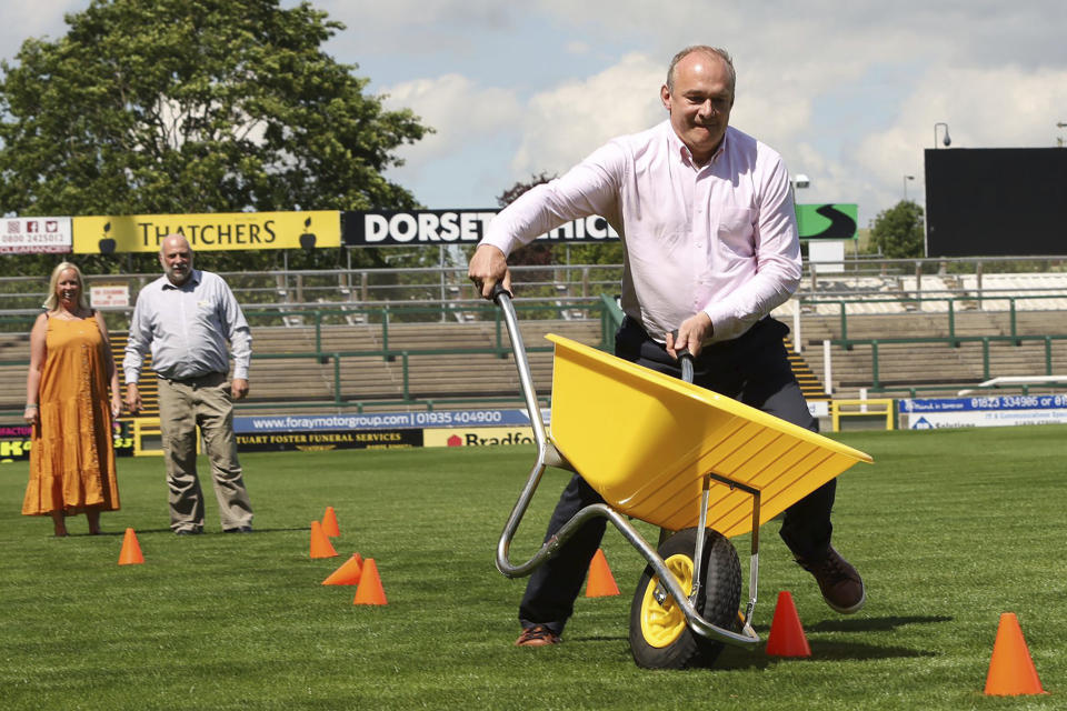 Britain's Liberal Democrats leader Ed Davey takes part in wheelbarrow racing at Huish Park, home of Yeovil Town football club in Yeovil, England, Monday June 17, 2024, while on the General Election campaign trail. (Will Durrant/PA via AP)