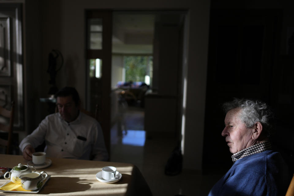 Farmer, Frans Dochy, 82, has breakfast with his son Bart at his family farm in Ledegem, Belgium, Tuesday, Feb. 13, 2024. Frans Dochy remembers harvesting beets out of the cold, thick earth by hand for hours, but states that 2024 regulations and bookkeeping would have driven him out of farming long ago. (AP Photo/Virginia Mayo)