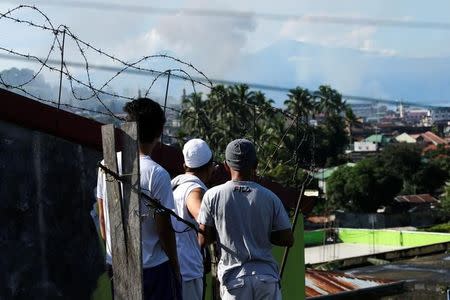 Men watch from a rooftop during the Philippines army airstrike as government troops continue their assault against insurgents from the Maute group in Marawi city June 27, 2017. REUTERS/Jorge Silva