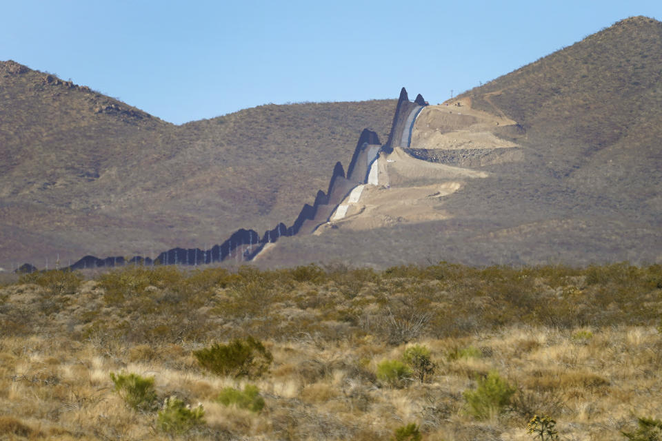 Newly erected border wall separating Mexico, left, and the United States, cuts through through the Sonoran Desert just west of the San Bernardino National Wildlife Refuge, Wednesday, Dec. 9, 2020, in Douglas, Ariz. Construction of the border wall, mostly in government owned wildlife refuges and Indigenous territory, has led to environmental damage and the scarring of unique desert and mountain landscapes that conservationists fear could be irreversible. (AP Photo/Matt York)