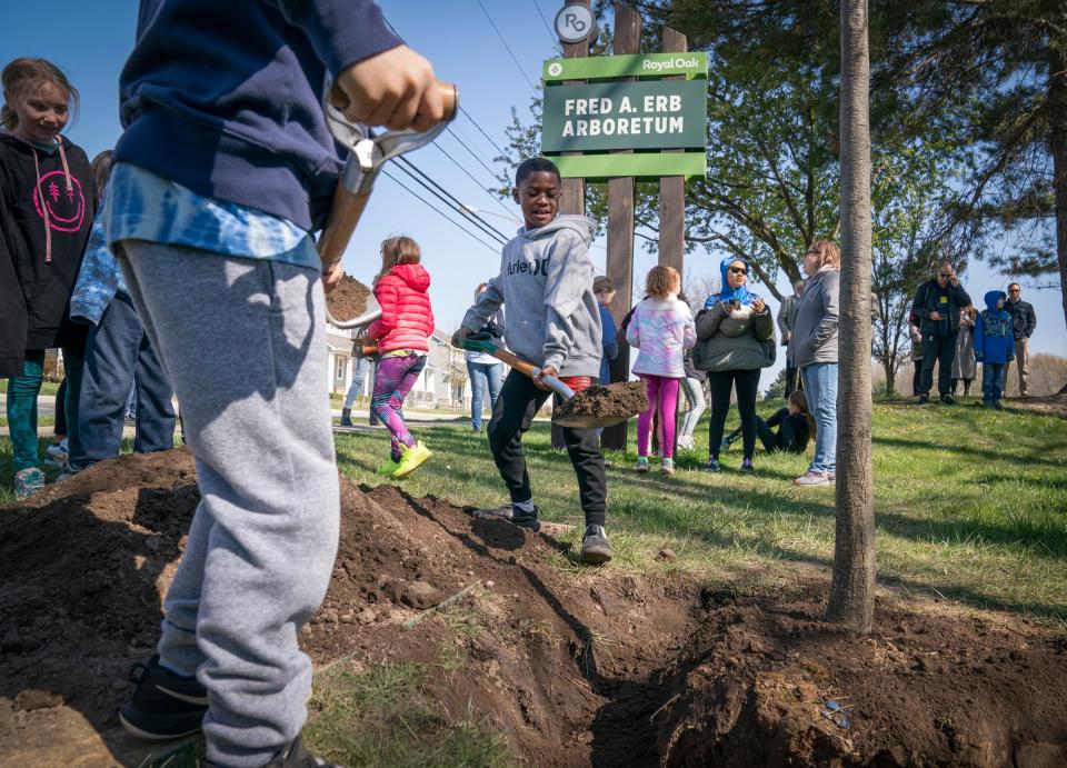 Kaiden Thomas, 8, a third grader from Addams Elementary School, middle, helps plant a pin oak as the Erb family honors the late philanthropic Fred Erb on what would have been his 100th birthday by planting 100 trees around the newly named in his name, Fred A. Erb Arboretum in Royal Oak on April 27, 2023.