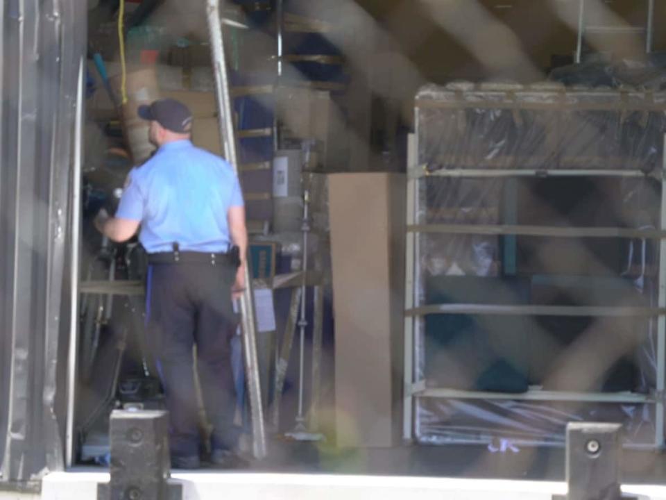 A Toronto police constable is seen in the Scarborough warehouse of a moving company accused of deceptive pricing. (CBC - image credit)