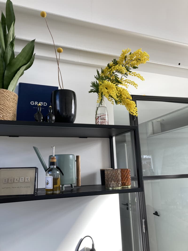 Black floating shelves with yellow flowers on top shelf