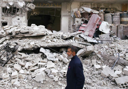 A man is seen near a damaged building in the besieged town of Douma, Eastern Ghouta, Damascus, Syria February 25, 2018. REUTERS/Bassam Khabieh