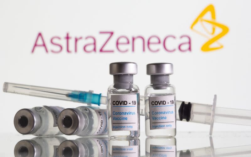 Vials labelled "COVID-19 Coronavirus Vaccine" and sryinge are seen in front of displayed AstraZeneca logo in this illustration