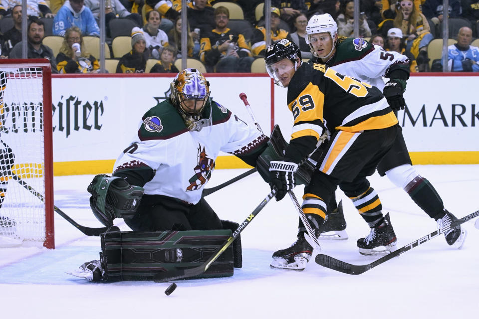 Arizona Coyotes goaltender Karel Vejmelka (70) stops a shot by Pittsburgh Penguins' Jake Guentzel (59) during the second period of an NHL hockey game Thursday, Oct. 13, 2022, in Pittsburgh. (AP Photo/Keith Srakocic)