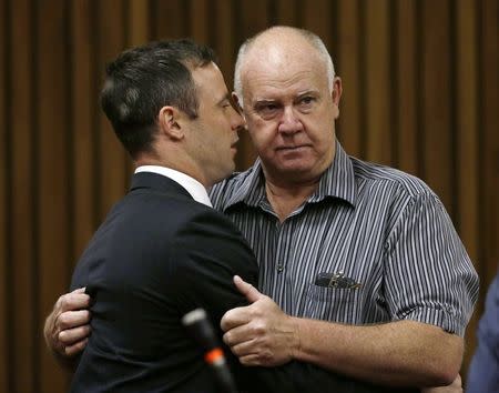 South African Olympic and Paralympic track star Oscar Pistorius (L) embraces his coach Ampie Louw ahead of his sentencing at the North Gauteng High Court in Pretoria October 21, 2014. REUTERS/Themba Hadebe/Pool