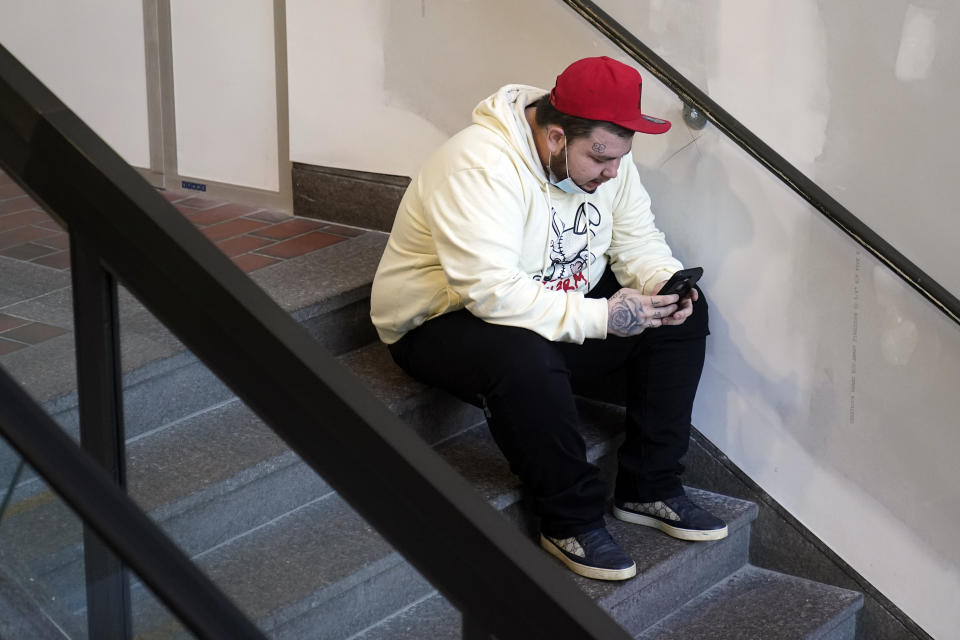 CORRECTS FIRST NAME TO DAMIK INSTEAD OF DARNIK - Damik Wright, the brother of Daunte Wright, sits in a stairwell as he waits for the rest of his family to arrive Tuesday, Nov. 30, 2021, at the Hennepin County Government Center in Minneapolis where jury selection begins for former suburban Minneapolis police officer Kim Potter, who says she meant to grab her Taser instead of her handgun when she shot and killed motorist Daunte Wright. (AP Photo/Jim Mone)