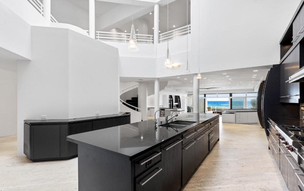 The Perlmutters' Palm Beach townhouse, listed for sale at $21 million, has a sleek kitchen with a center work island and an ocean view through the living area's glass doors.
