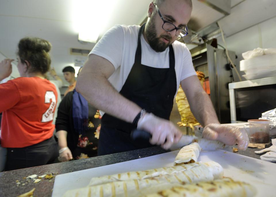 Bassam Dabbah prepares chicken shawarma wraps during a celebration of World Refugee Day by the International Institute of Erie at the SafeNet Big Backyard Children's Garden in Erie. He owns Shawarma Station, which will serve the classic Indian roast chicken dish at the Food Hall.