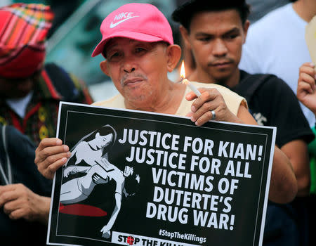 A man holds a candle and a placard seeking justice for 17-year-old high school student Kian delos Santos, who was killed in a recent police raid in an escalation of President Rodrigo Duterte's war on drugs, during a protest in front of the Philippine National Police (PNP) headquarters in Quezon city, Metro Manila, Philippines August 23, 2017. REUTERS/Romeo Ranoco