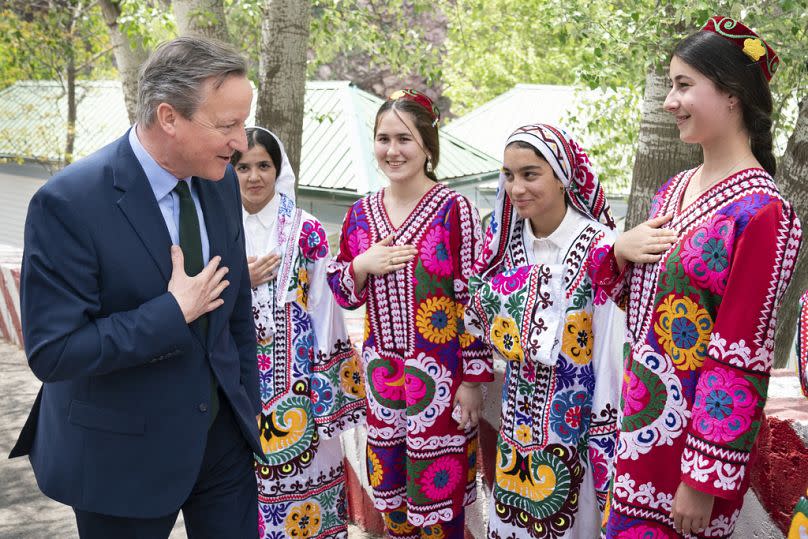 UK Foreign Secretary David Cameron is greeted by women in traditional costumes as he visits the Nurek Hydro-Electric Project, some 70 km south of Dushanbe, 22 April 2024