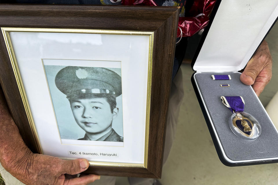 Wilfred Ikemoto holds a photo of his older brother, Haruyuki Ikemoto, and the Purple Heart medal posthumously awarded to him, in Pearl Harbor, Hawaii, on Friday, May 10, 2024. The families of five Hawaii men who served in a unit of Japanese-language linguists during World War II received posthumous Purple Heart medals on behalf of their loved ones on Friday, nearly eight decades after the soldiers died in a plane crash in the final days of the conflict. (AP Photo/Audrey McAvoy)