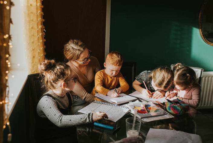 Single Mum in a home environment home schools / helps her children with homework. Recognisable scene for parents in lockdown attempting to juggle a work / life balance during the Coronavirus pandemic.