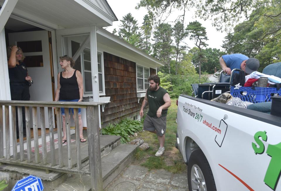 Barnstable County Sheriff Deputy Mary Beth Robichaud, left, talks with tenant Alessandra Dabliz as movers finish loading a truck. Following a court proceeding, Dabliz and her brother George Paznola were evicted from 51 Dunns Pond Road in Hyannis.