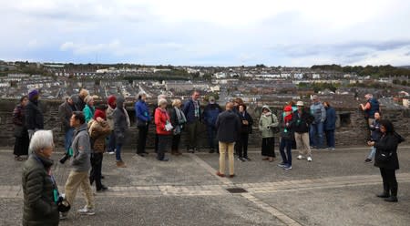 Tourists listen to a tour guide as they stand on the walls overlooking the Bogside area of Londonderry, Northern Ireland