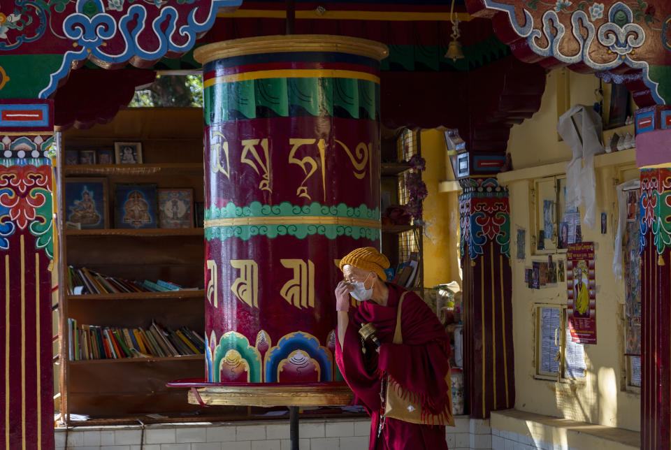 An exile Tibetan Buddhist monk wearing a mask as precaution against the coronavirus rotates a prayer wheel in Dharmsala, India, Friday, Dec. 18, 2020. (AP Photo/Ashwini Bhatia)