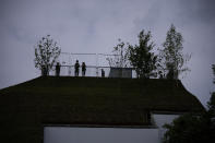 A police officer and a community support officer are silhouetted as they stand by the viewing area of the newly built "Marble Arch Mound" after it was opened to the public next to Marble Arch in London, Tuesday, July 27, 2021. The temporary installation commissioned by Westminster Council and designed by architects MVRDV has been opened as a visitor attraction to try and entice shoppers back to the adjacent Oxford Street after the coronavirus lockdowns. (AP Photo/Matt Dunham)