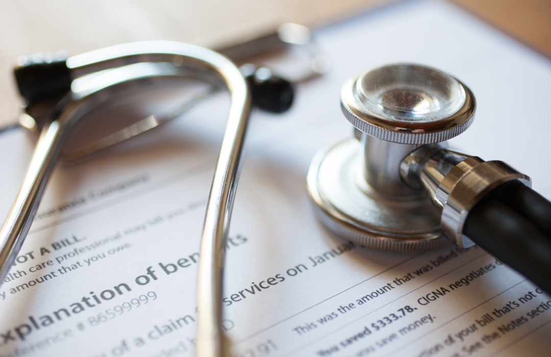 A stethoscope sitting on top of health insurance benefits document.