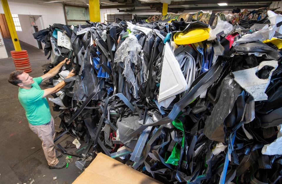 Ross Gibby, chief operating officer for CRDC global, stands in front of a backdrop of mixed plastic recycling from a corporate customer.