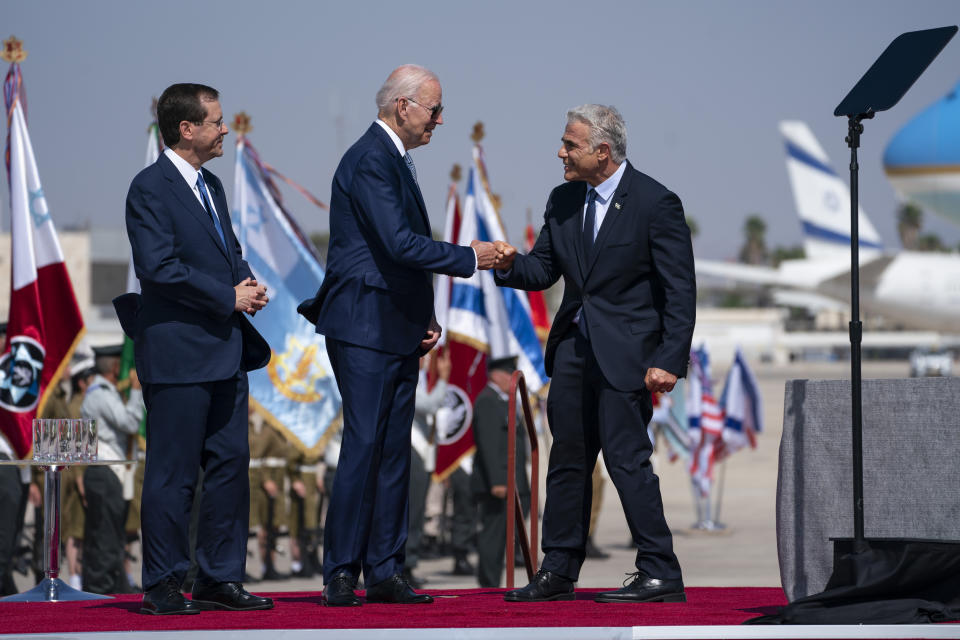 Israeli President Isaac Herzog, left, looks on as President Joe Biden gives a fist bump to Israeli Prime Minister Yair Lapid during an arrival ceremony after arriving at Ben Gurion Airport, Wednesday, July 13, 2022, in Tel Aviv. (AP Photo/Evan Vucci)