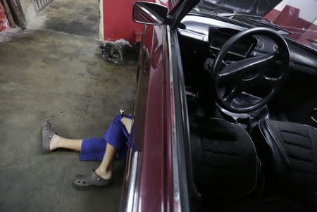 A mechanic works on a Lada at a car workshop in Havana February 9, 2015. REUTERS/Enrique De La Osa