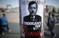 <p>People walk past a poster depicting Turkish Prime Minister Tayyip Erdogan that has been pasted by demonstrators at Taksim Square in Istanbul June 5, 2013. (Stoyan Nenov/Reuters) </p>