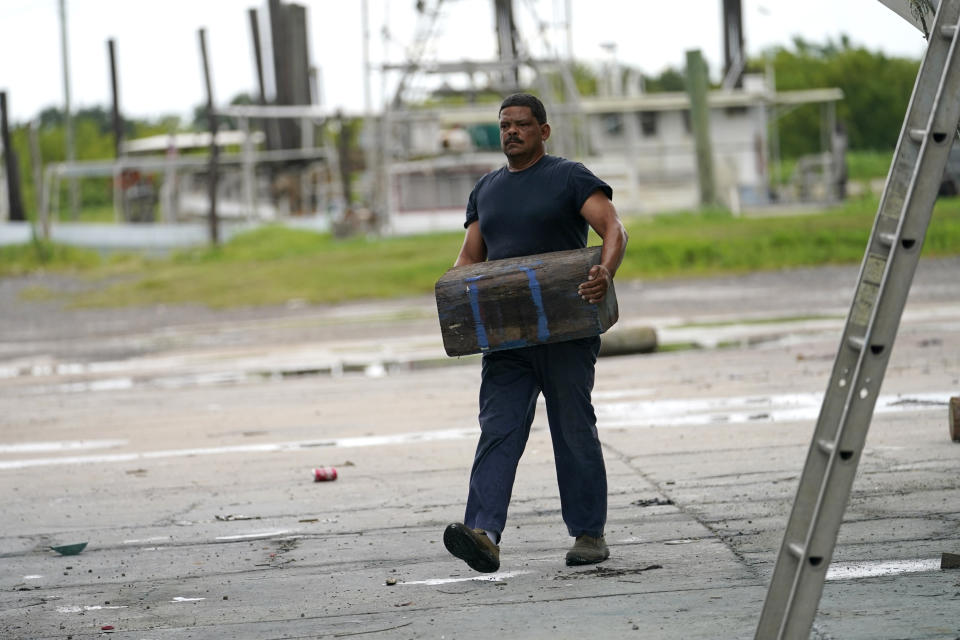 Mike Bartholemey carries a block to place under his recently dry-docked shrimp boat, out of concern for strong winds, in Empire, La., Sunday, Aug. 23, 2020, in advance of Hurricane Marco, expected to make landfall on the Southern Louisiana coast. (AP Photo/Gerald Herbert)