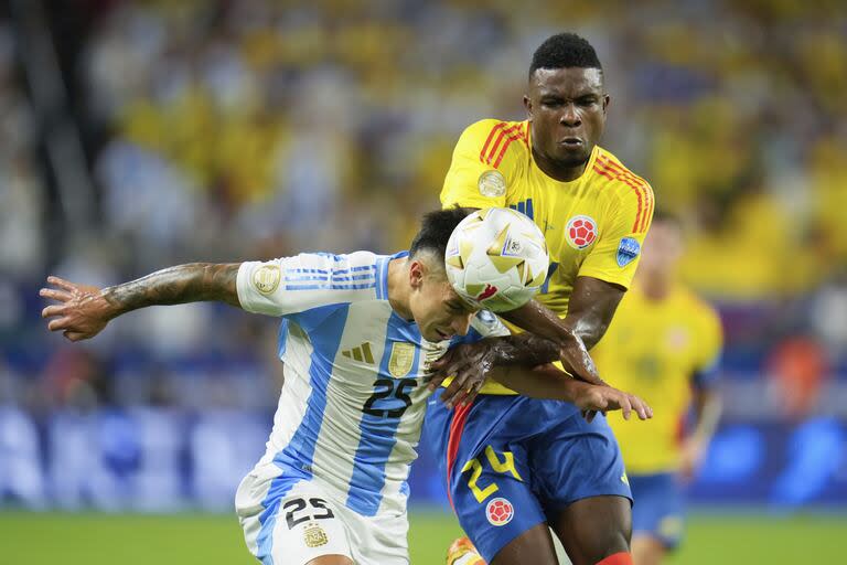 Lisandro Martínez cabecea la pelota desafiado por el colombiano Jhon Córdoba.