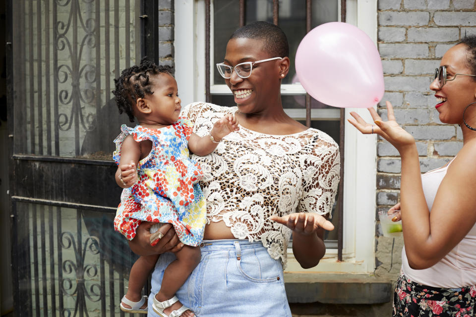 Smiling mother holding her daughter next to a friend