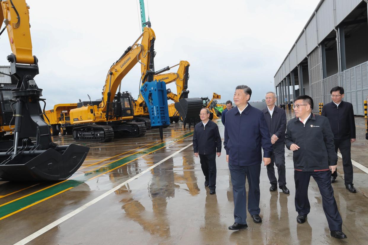 Xi Jinping among a group of other men visiting a factory.