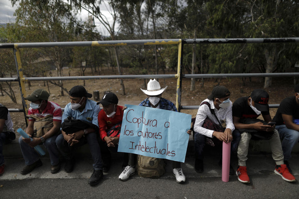 A supporter of Honduran environmental and Indigenous rights activist Berta Caceres holds a sign that reads in Spanish "Capture the masterminds" during the trial against Roberto David Castillo, an alleged mastermind of her murder, outside of the Supreme Court building in Tegucigalpa, Honduras, Tuesday, April 6, 2021. The trial began five years after the prize-winning activist's murder. (AP Photo/Elmer Martinez)