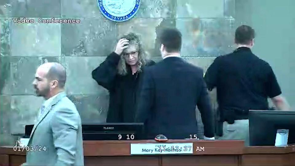 In this image from video provided by the Clark County District Court, Judge Mary Kay Holthus is seen cradling her head after a defendant launched over her desk during his sentencing in a felony battery case, Wednesday, Jan. 3, 2024 in Las Vegas. Authorities say the judge suffered minor injuries n the attack while a courtroom marshal suffered a bleeding gash on his forehead and a dislocated shoulder.