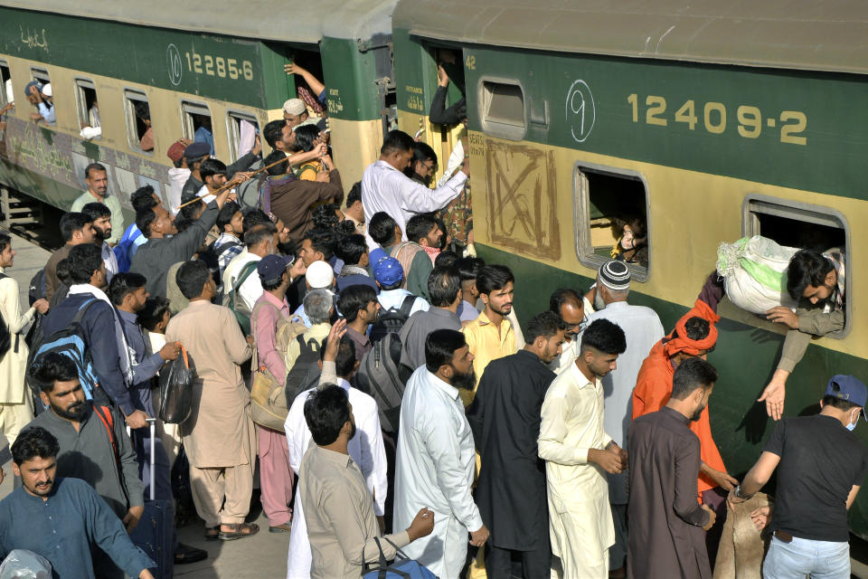 People board a passenger train to reach their villages and cities to celebrate the upcoming Eid al-Fitr holidays, marking the end of the Islamic holy month of Ramadan, in Lahore, Pakistan, Thursday, April 20, 2023. (AP Photo/Pervez Masih)