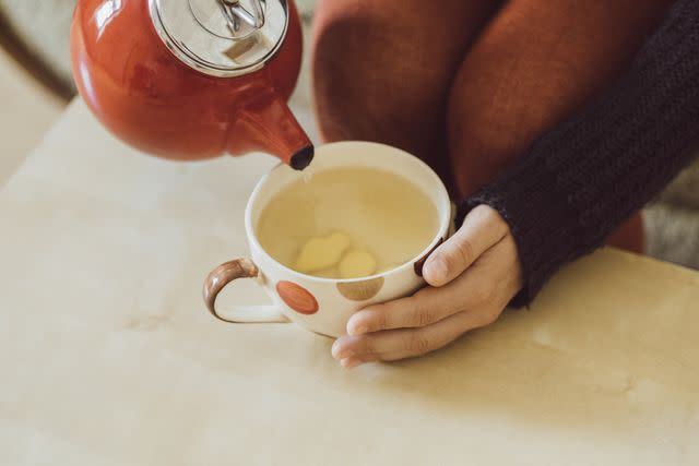 <p>Westend61 / Getty Images</p> Serving warm tea made with fresh ginger