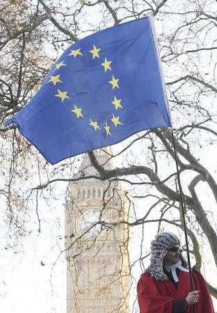 A protester wearing judge's wigs and robes waves a European Union flag from an open top bus as it drives past the Supreme Court ahead of the challenge against a court ruling that Theresa May's government requires parliamentary approval to start the process of leaving the European Union, in Parliament Square, central London, Britain December 5, 2016. REUTERS/Toby Melville