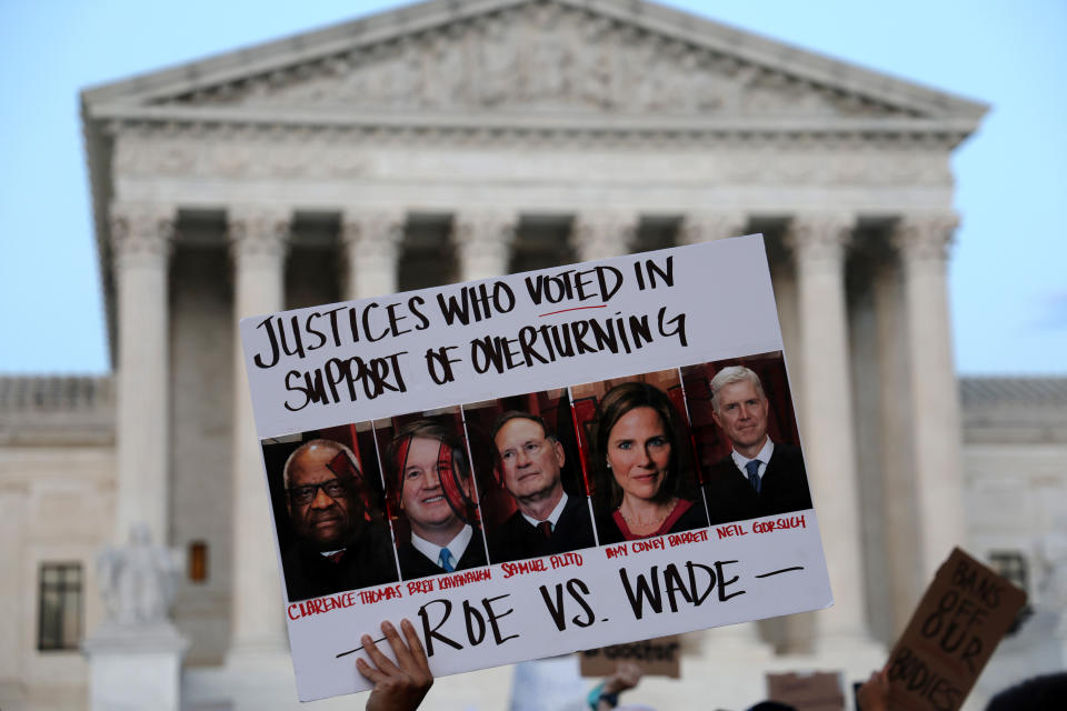 A person holds up a sign displaying photos of five Supreme Court justices and the words: Justices Who Voted in Support of Overturning Roe vs. Wade.
