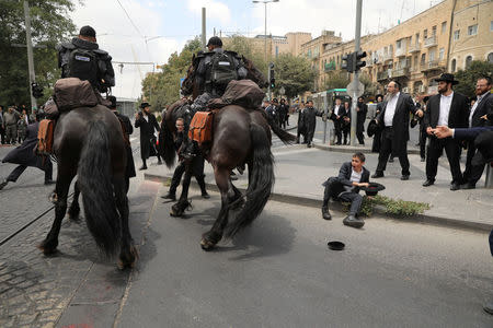 Mounted Israeli police try to prevent ultra-Orthodox Jewish men from blocking a road as they protest against the detention of one of their community members who evaded a military draft order, in Jerusalem August 2, 2018. REUTERS/Ammar Awad