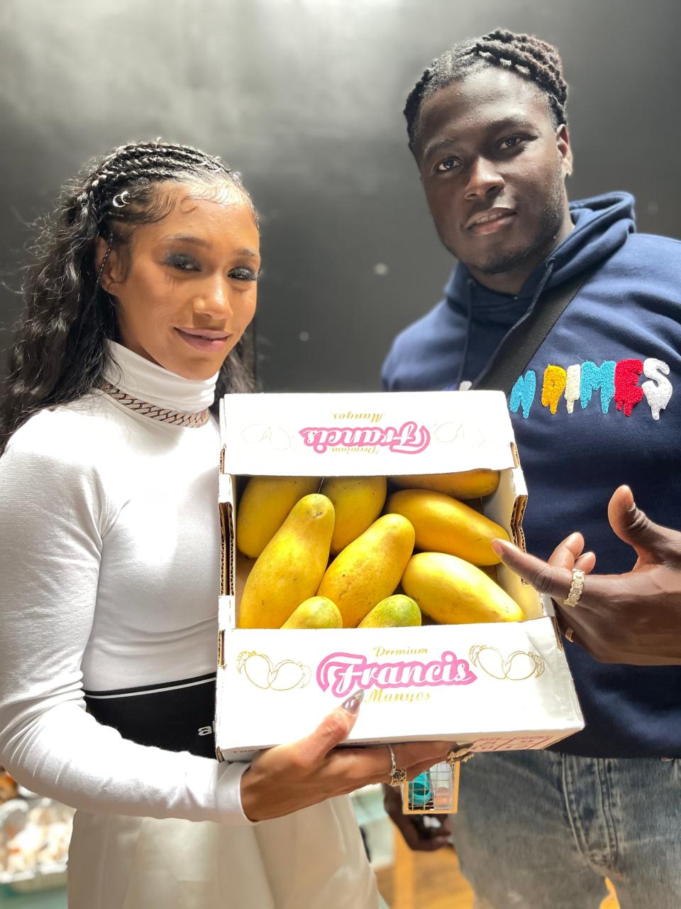 Kervin Edouard, 33, left, owner of Mango Man Swerv, a Haitian mango exportation company, with Bia, a Boston rapper, hold up a box of Francis mangos imported from Haiti on June 3, 2021.