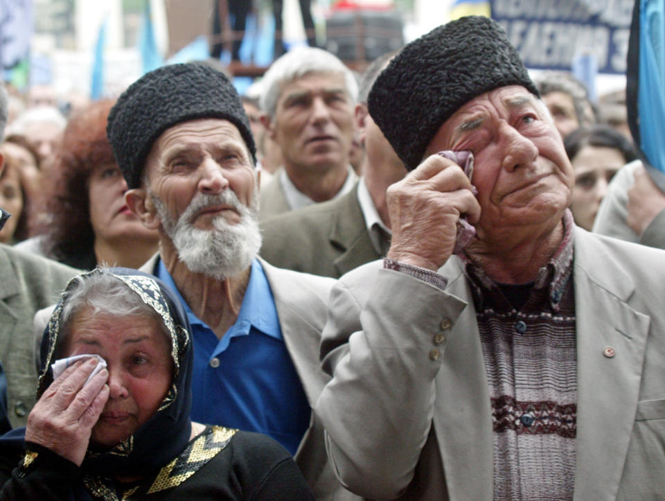 FILE - In this May 18, 2004 file photo, Crimean Tatars wipe away their tears at a mourning rally during the 60th anniversary of deportation of ethnic Tatars under Soviet dictator Josef Stalin, in the Crimean capital of Simferopol, Ukraine. The fate of Crimean Tatars is one of the top issues at the inaugural meeting of the Crimean Platform on Monday Aug. 23, 2021, an international summit called by Ukraine to build up pressure on Russia over the annexation that has been denounced as illegal by most of the world. (AP Photo/Efrem Lukatsky, File)