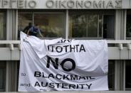 A security guard removes a banner placed earlier by protesters from a balcony of the Finance Ministry in Athens, Greece, July 1, 2015. REUTERS/Yannis Behrakis